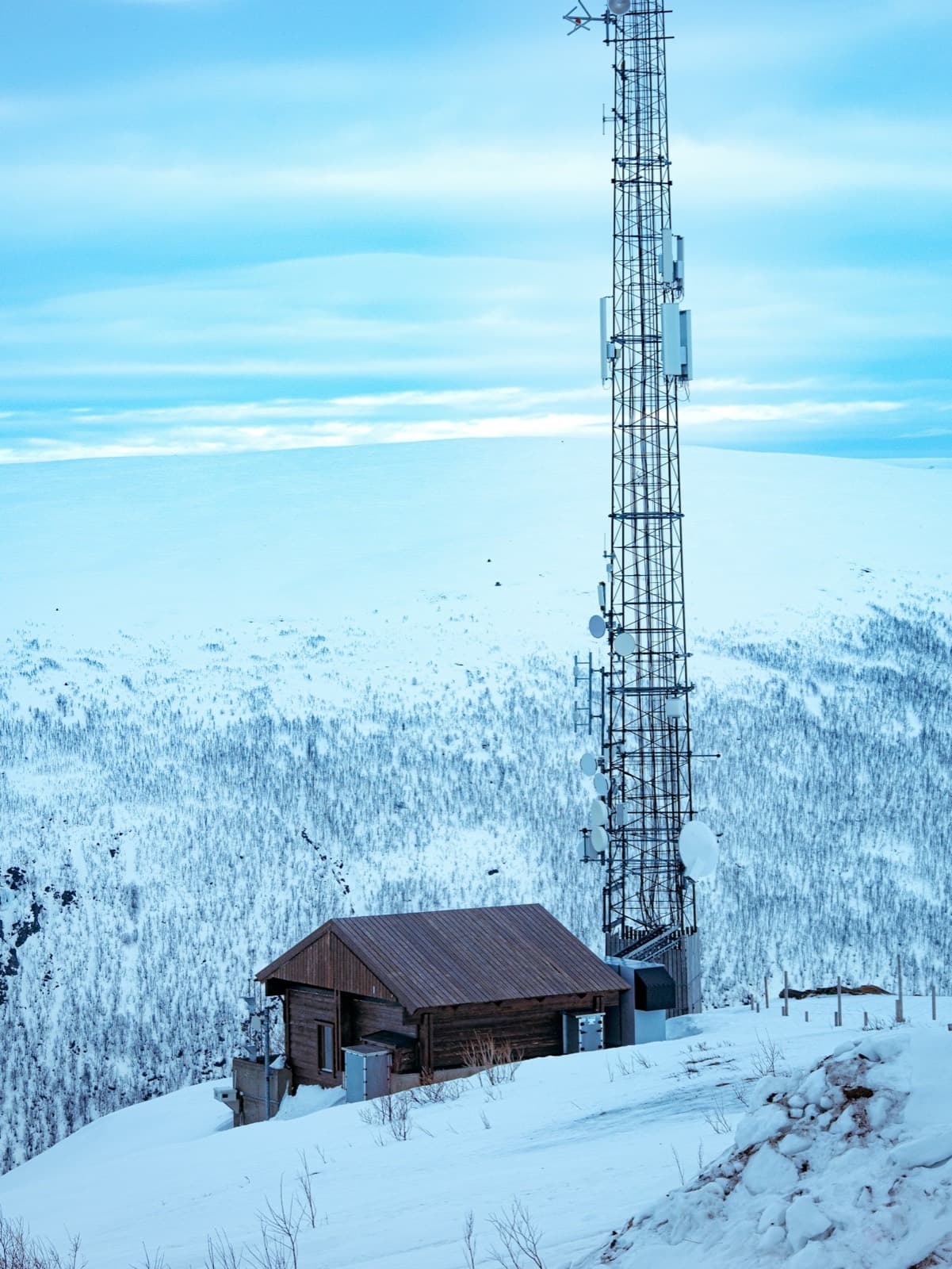 A relay mast and equipment hut on a snow-covered hillside
